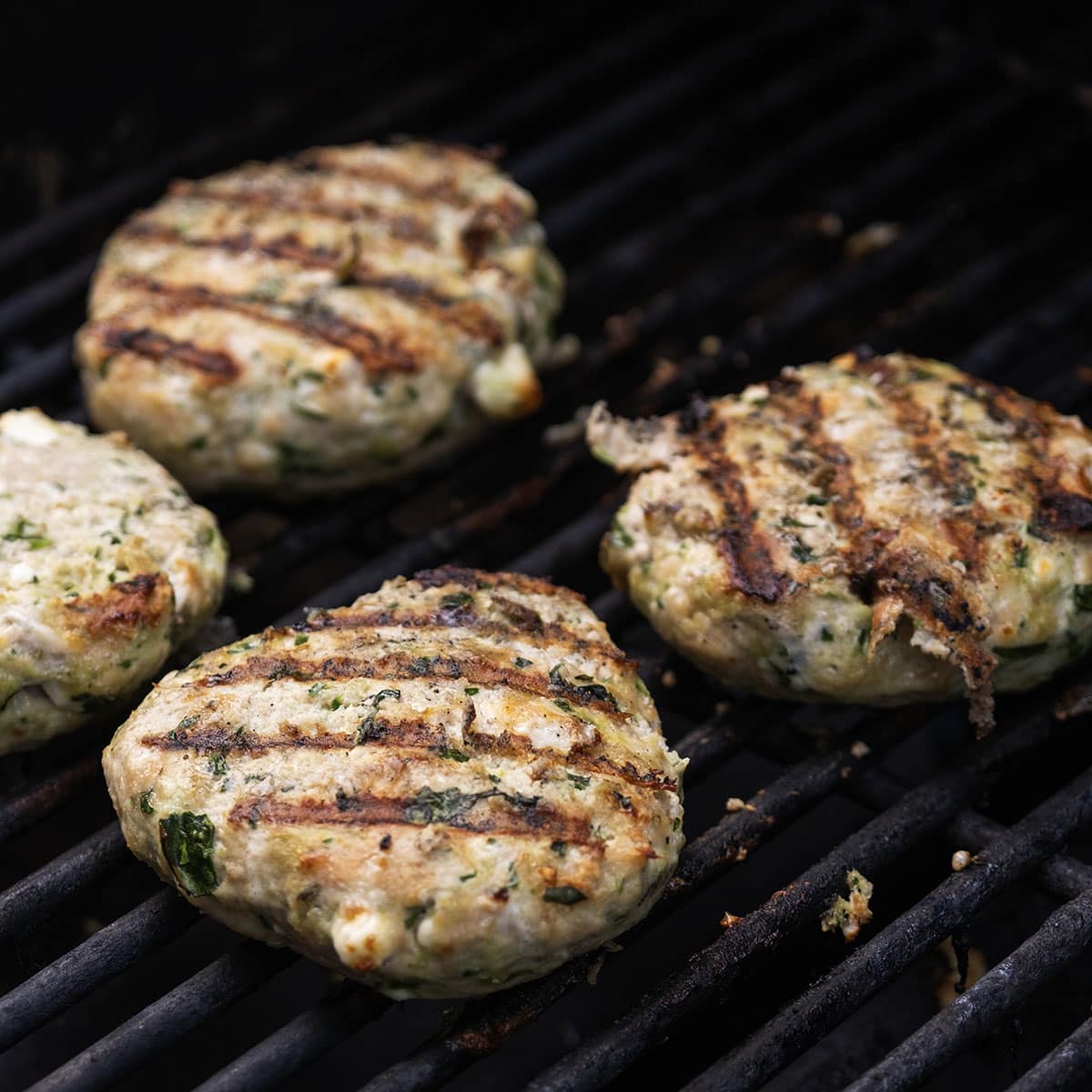Chicken patties on the grill flipped over with grill marks.