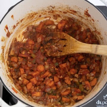 Tomato paste caramelizing with vegetables in dutch oven.