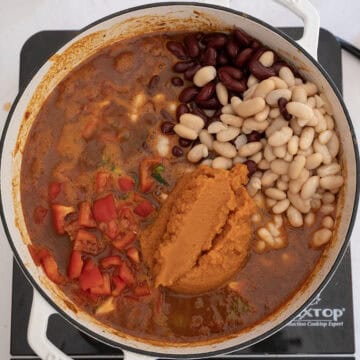 Beans, peppers, and pumpkin puree added to the chili in the dutch oven.