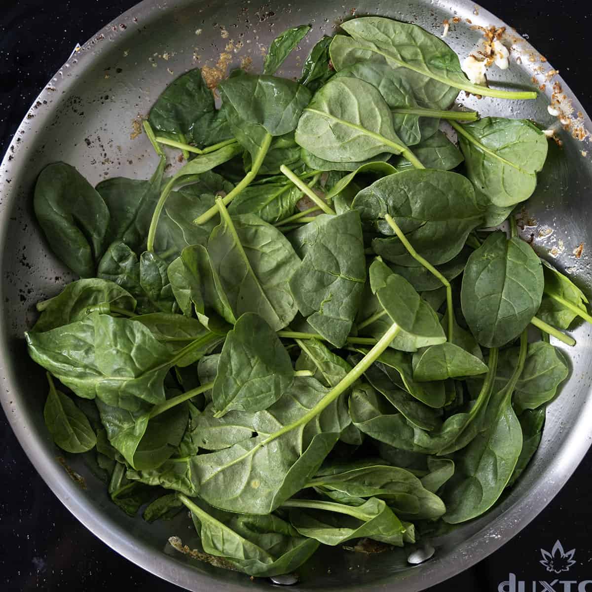 Sauteing spinach in a pan.