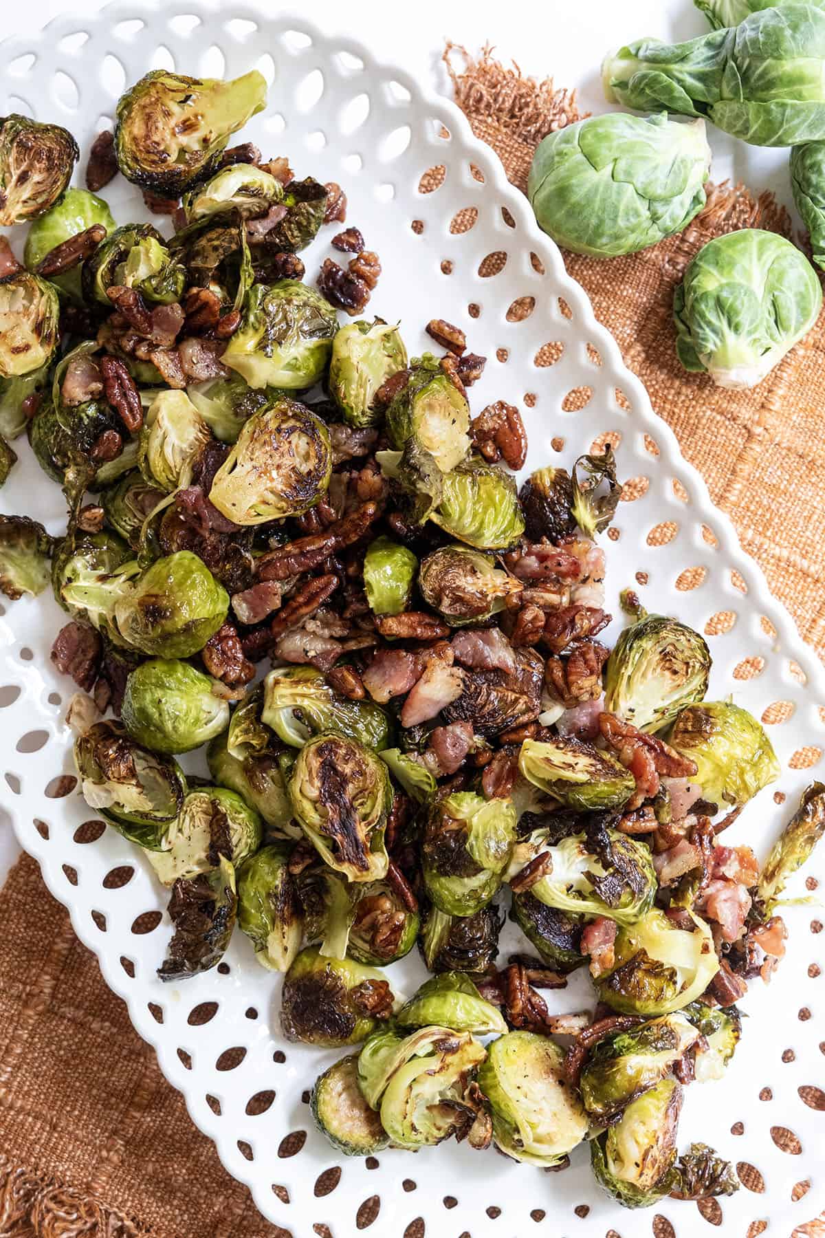 Roasted Brussels sprouts on a plate with bacon and pecans.