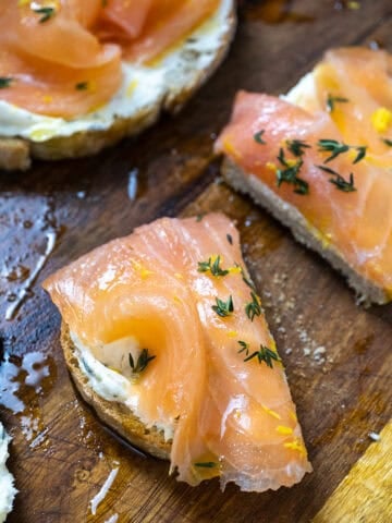 Lox on top of mascarpone toast on a cutting board with an old school butter knife covered in mascarpone.