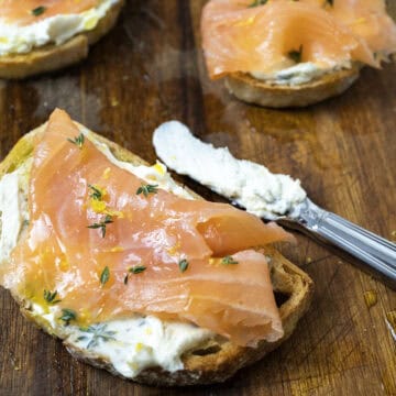 Lox on top of mascarpone toast on a cutting board with an old school butter knife covered in mascarpone.