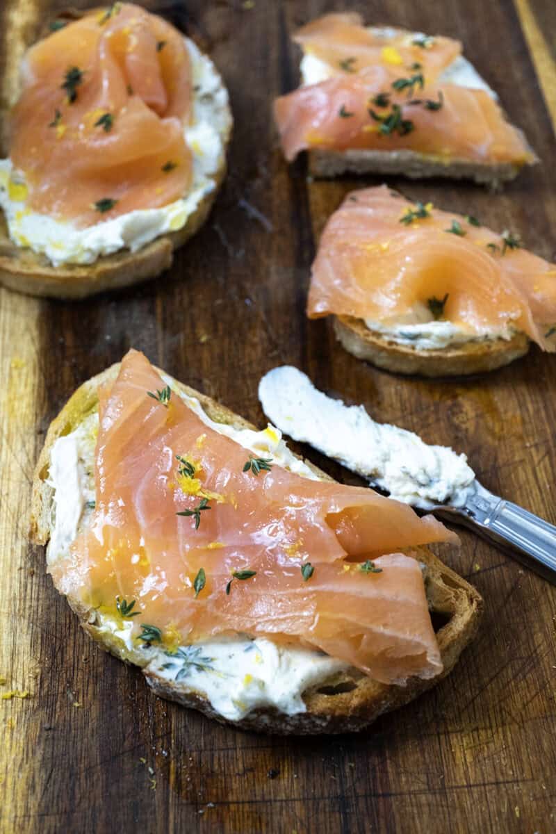 3 pieces of mascarpone toast topped with lox on a cutting board. 