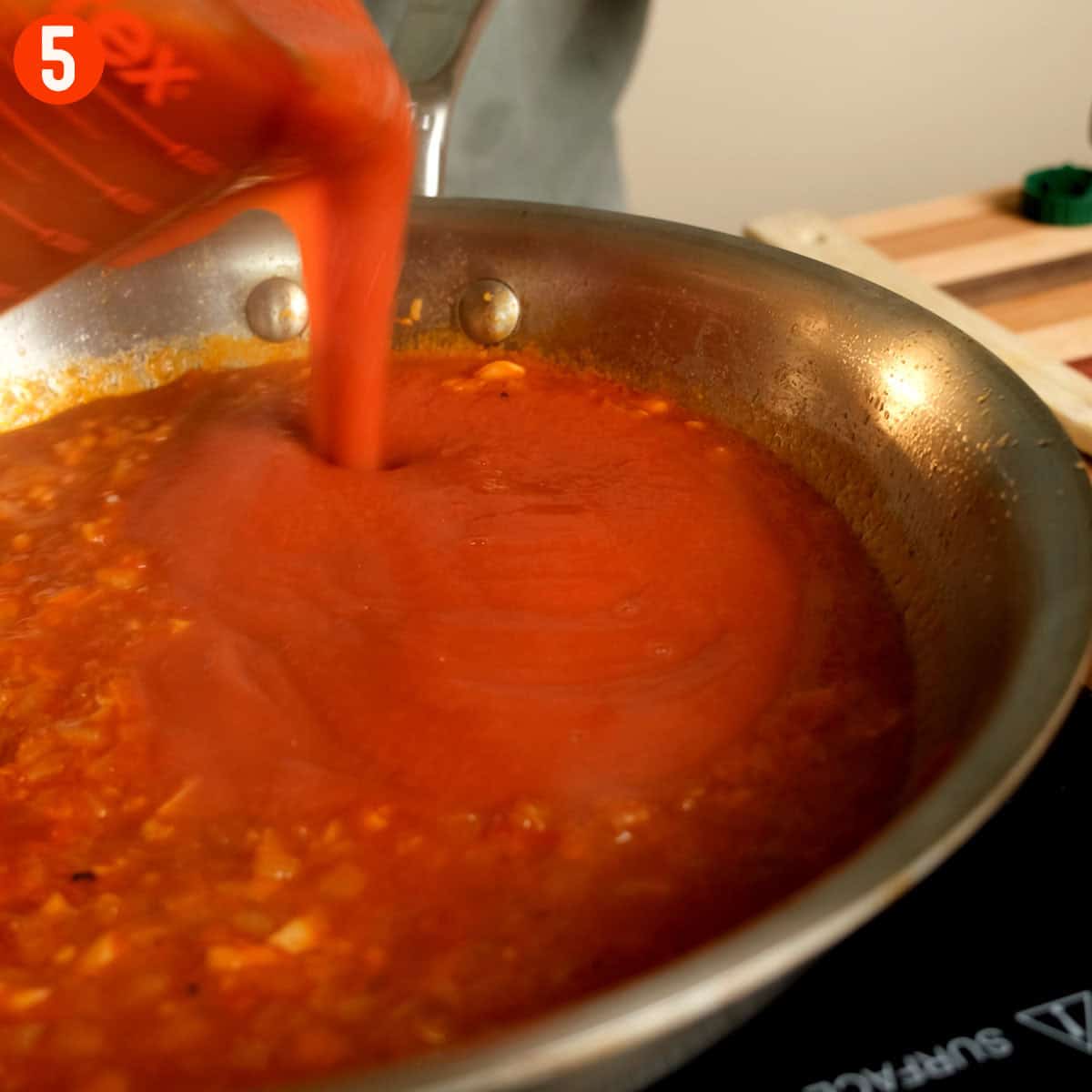 Pouring tomato passata into saucepan.