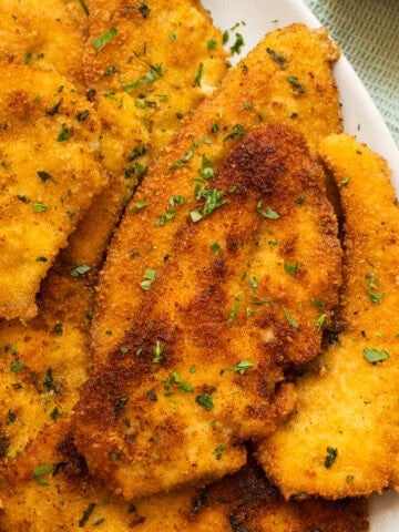 Italian chicken cutlets on piled on a plate.