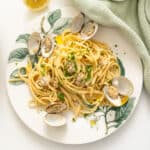 Linguine with clams served on a plate with an extra lemon.