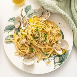Linguine with clams served on a plate with an extra lemon.