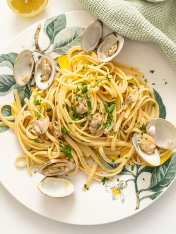 Linguine with clams served on a plate with an extra lemon.