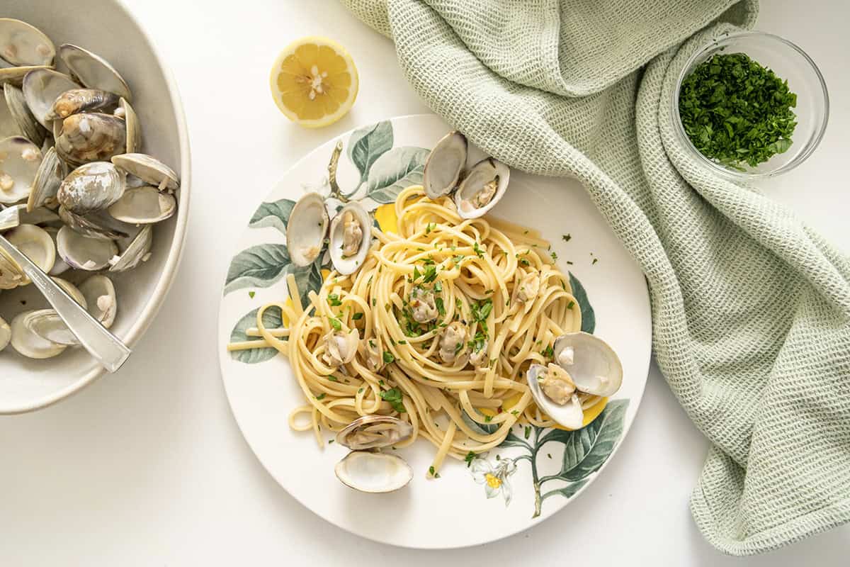 Linguine with clams served on a plate with an extra lemon. 