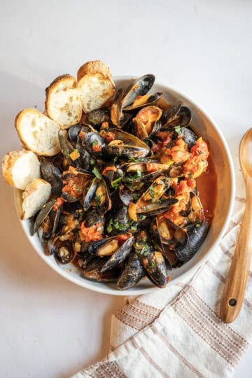 Mussels Fra Diavolo with crusty Italian bread in a serving bowl.