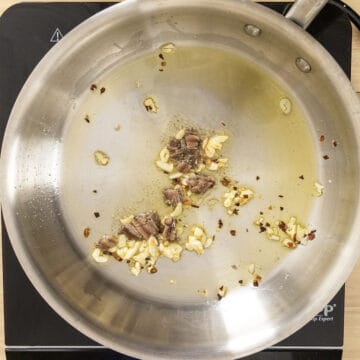 Anchovies combined with garlic in a pan.
