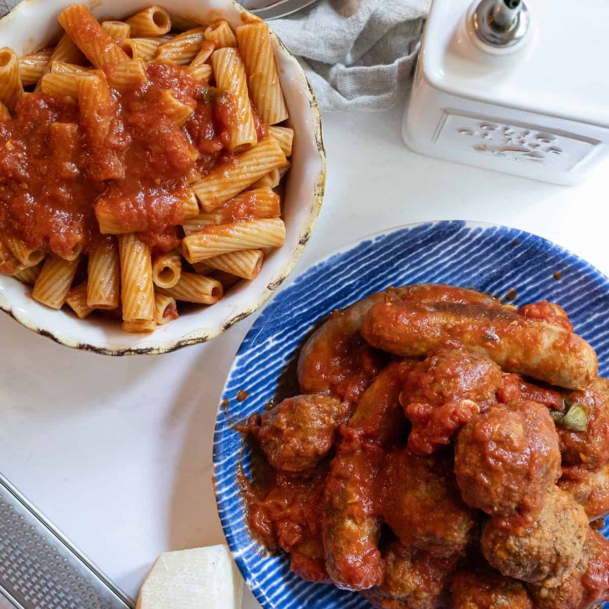 Sunday Sauce over pasta with a plate of meatballs and sausage.