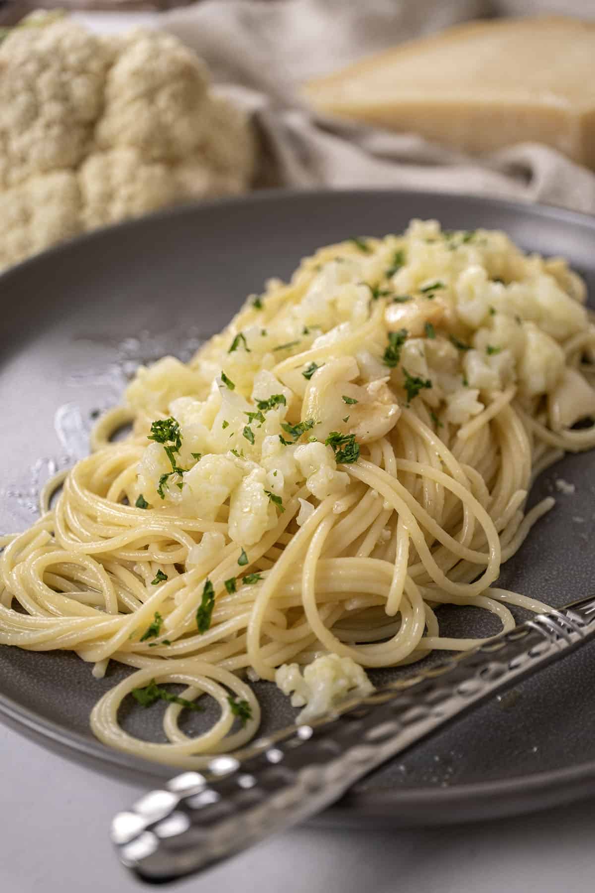 spaghetti with cauliflower plated on a dish garnished with parsley.