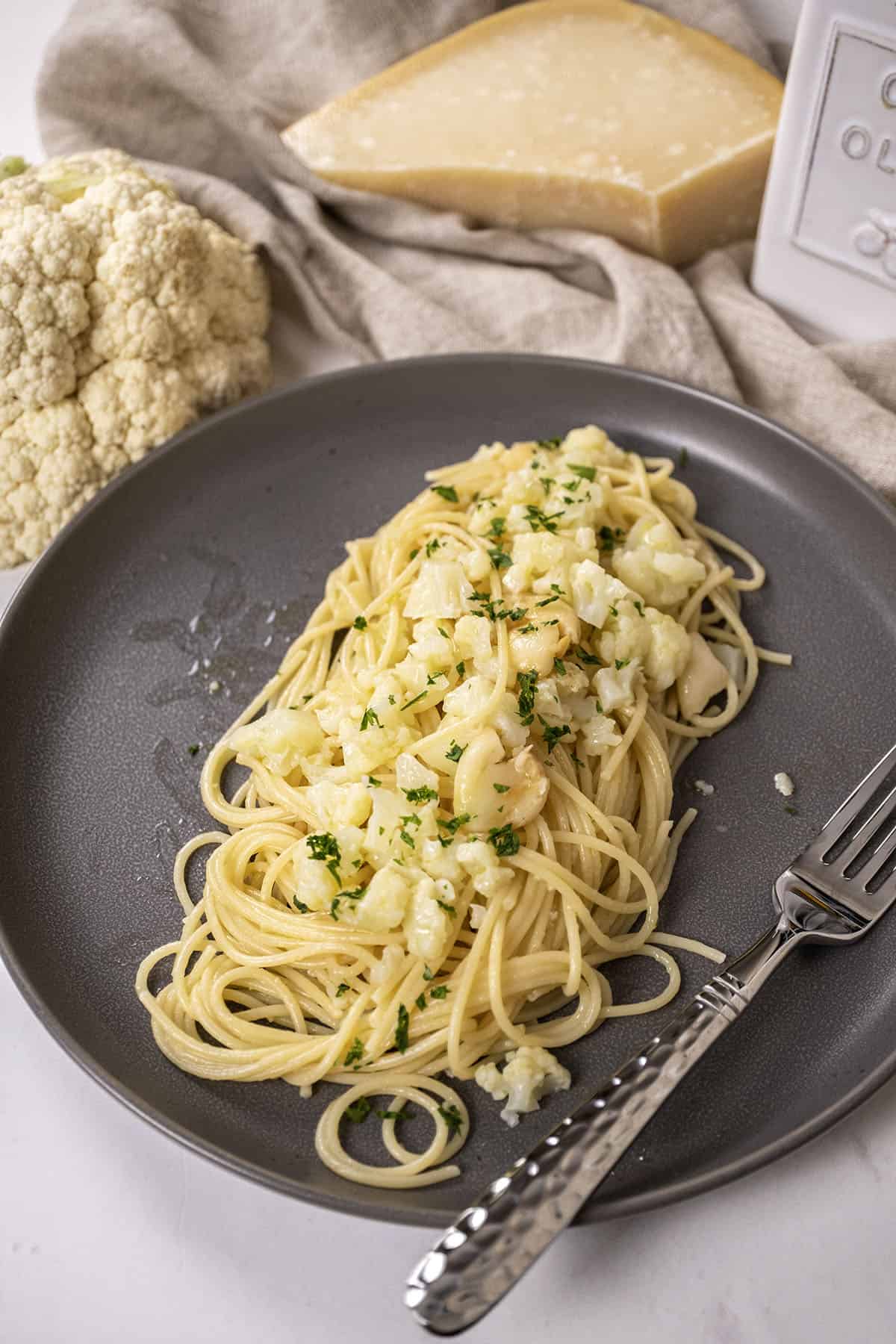 spaghetti with cauliflower plated on a dish garnished with parsley.