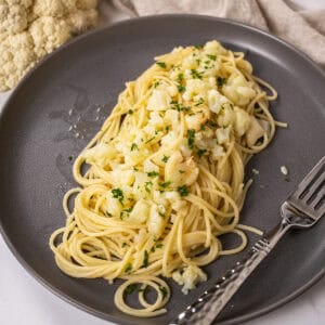 spaghetti with cauliflower plated on a dish garnished with parsley.