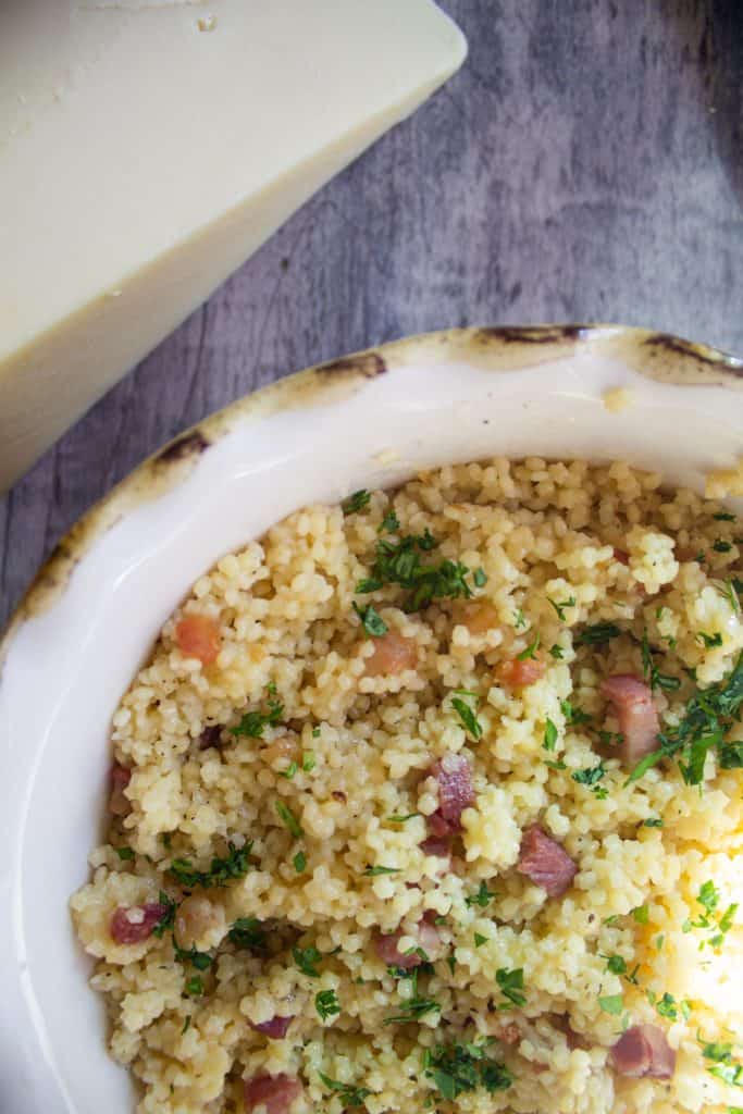 pastina with parmesan, parsley, and pancetta in a gold rimmed bowl.