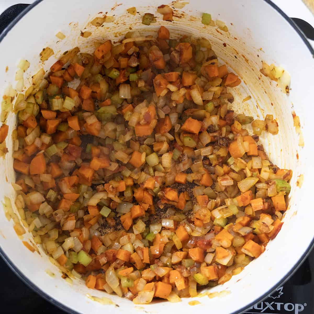 carrots, onions, and celery combined with tomato paste in the dutch oven.