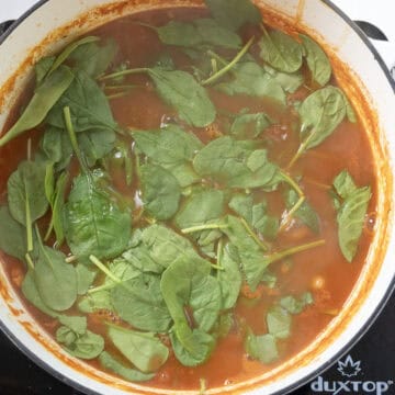 Spinach added on top of the soup in the dutch oven.