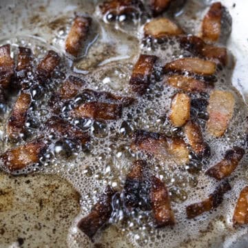 Guanciale frying in its own fat in a sauce pan.