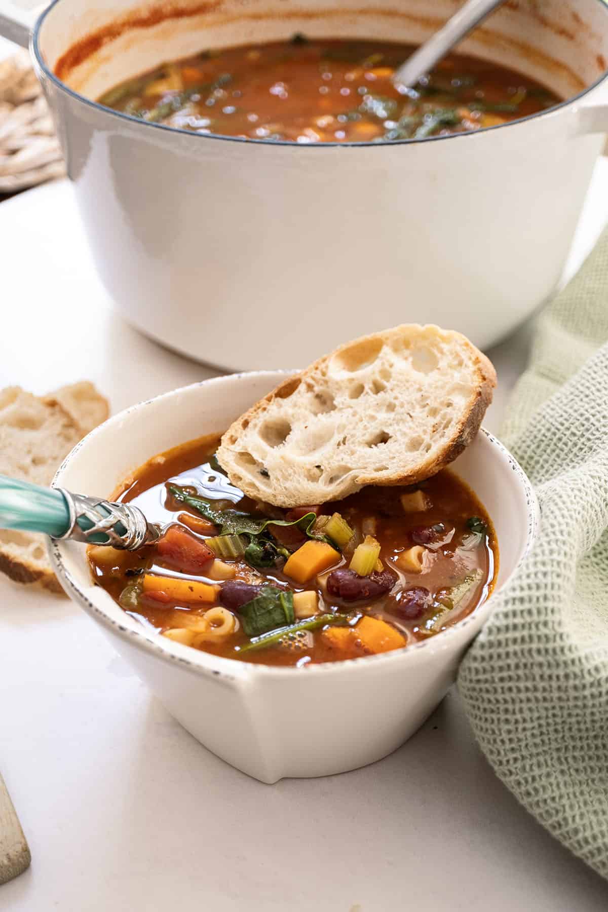 A bowl of minestrone with a piece of Italian bread.