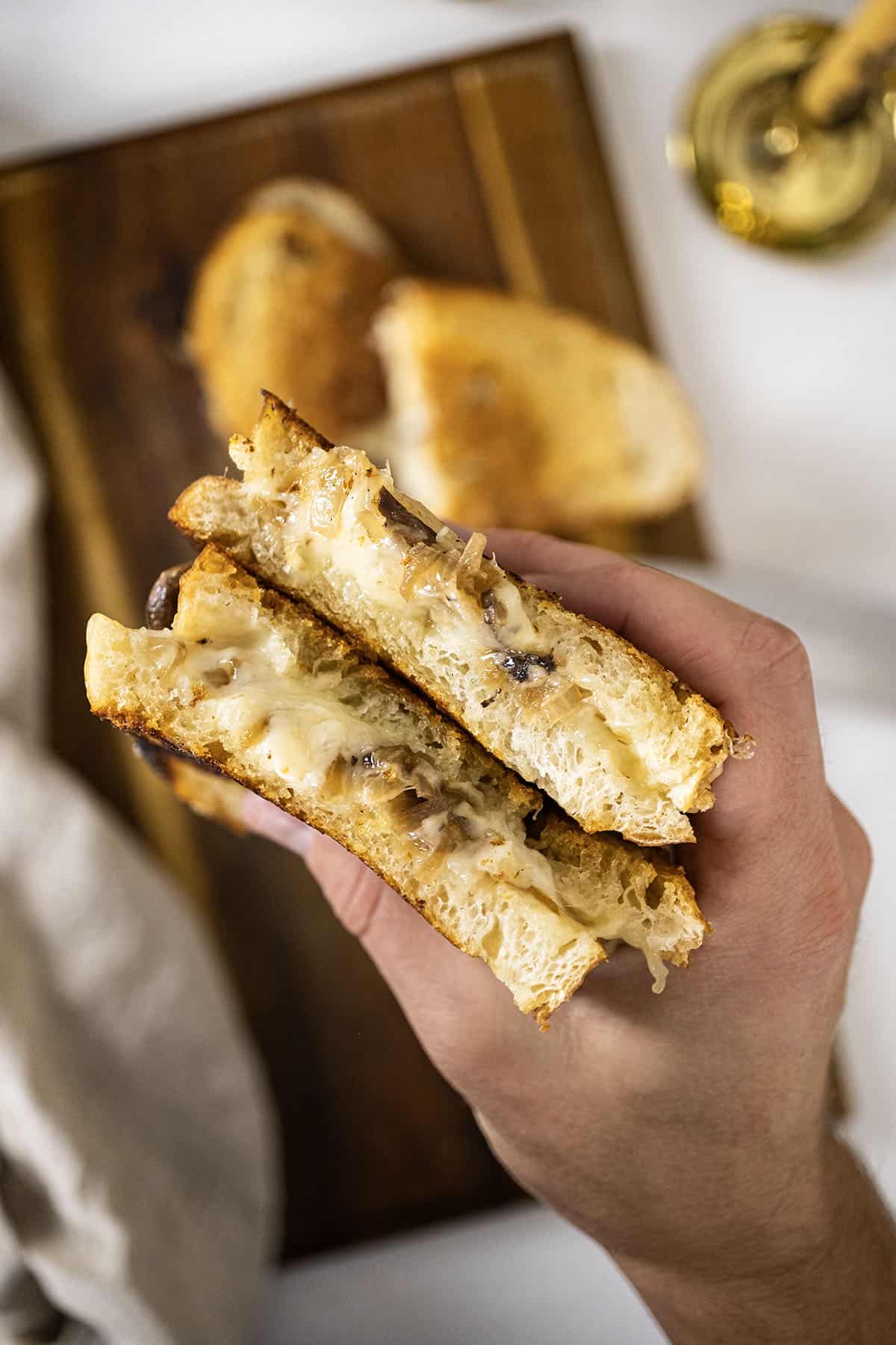 Hand holding two halves of a grilled cheese. 