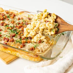 Spooning Italian mac and cheese out of a baking dish.