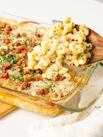 Spooning Italian mac and cheese out of a baking dish.