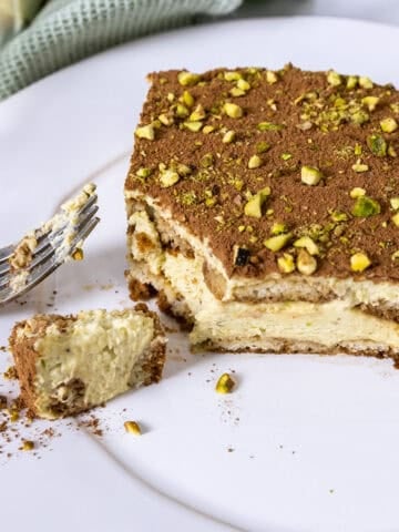 Pistachio Cream tiramisu on a plate with a forkful scooped out.