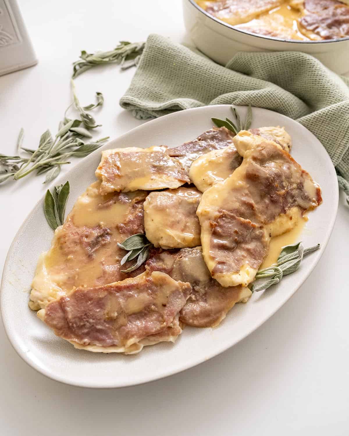 Chicken saltimbocca on a serving plate topped with fresh sage leaves.