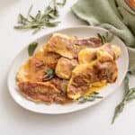 Chicken saltimbocca on a serving plate topped with fresh sage leaves.
