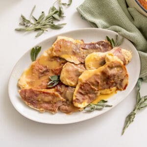 Chicken saltimbocca on a serving plate topped with fresh sage leaves.