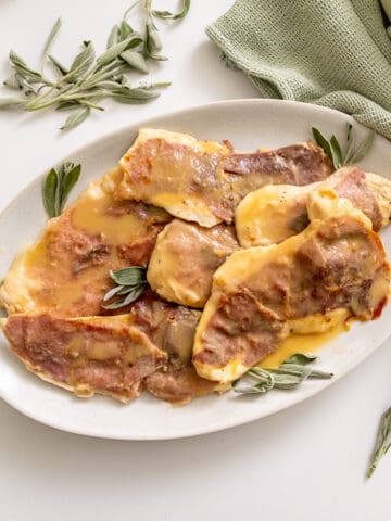 Chicken saltimbocca on a serving plate topped with fresh sage leaves.
