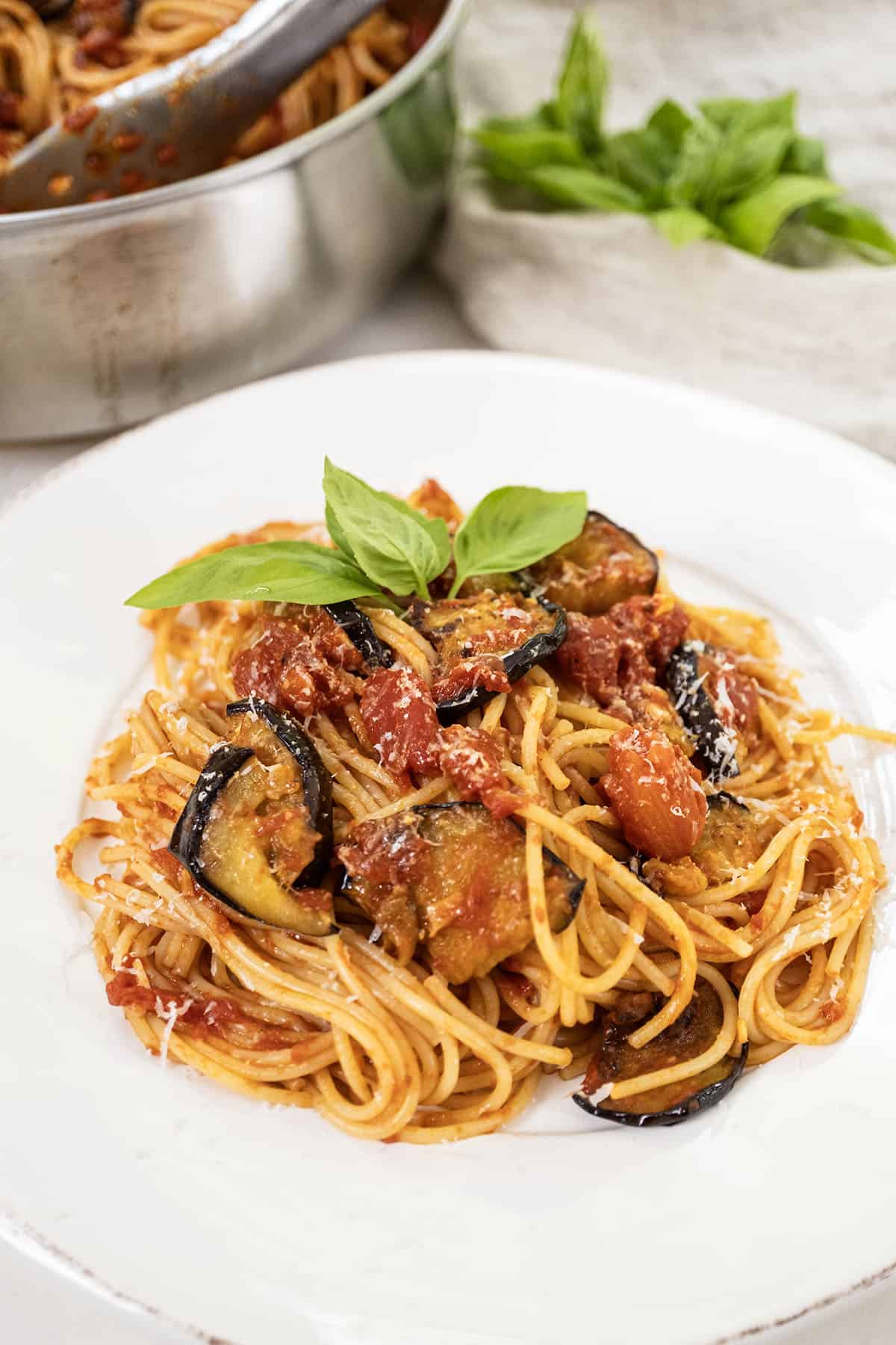 Pasta alla norma plated on a dish and garnished with basil.