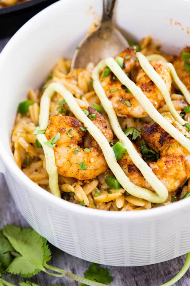 close-up of spicy shrimp topped with avocado crema over creamy cilantro lime orzo