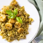 Shrimp over pesto pasta garnished with basil.