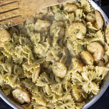 Pesto combined with pasta and shrimp in the pan.