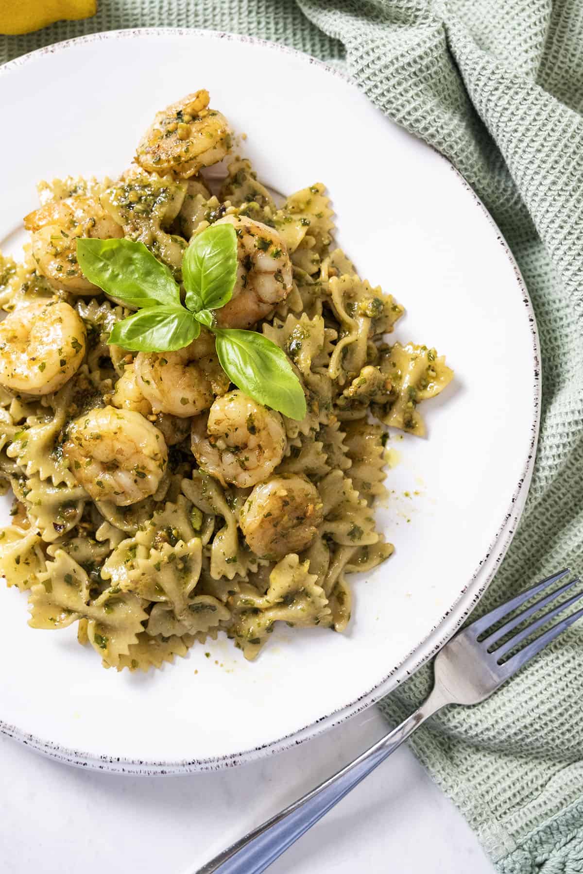 Shrimp over pesto pasta garnished with basil.