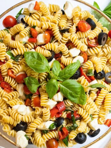Italian pasta salad in large bowl garnished with basil.