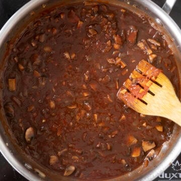 Red wine and chicken broth added to saucepan with vegetables.