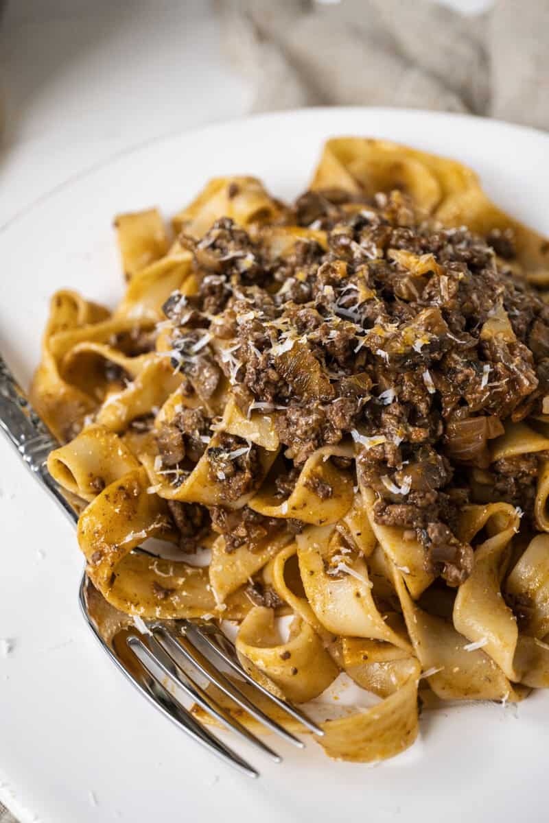 Lamb ragu over pappardelle on a small plate.