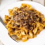 Lamb ragu over pappardelle on a small plate.