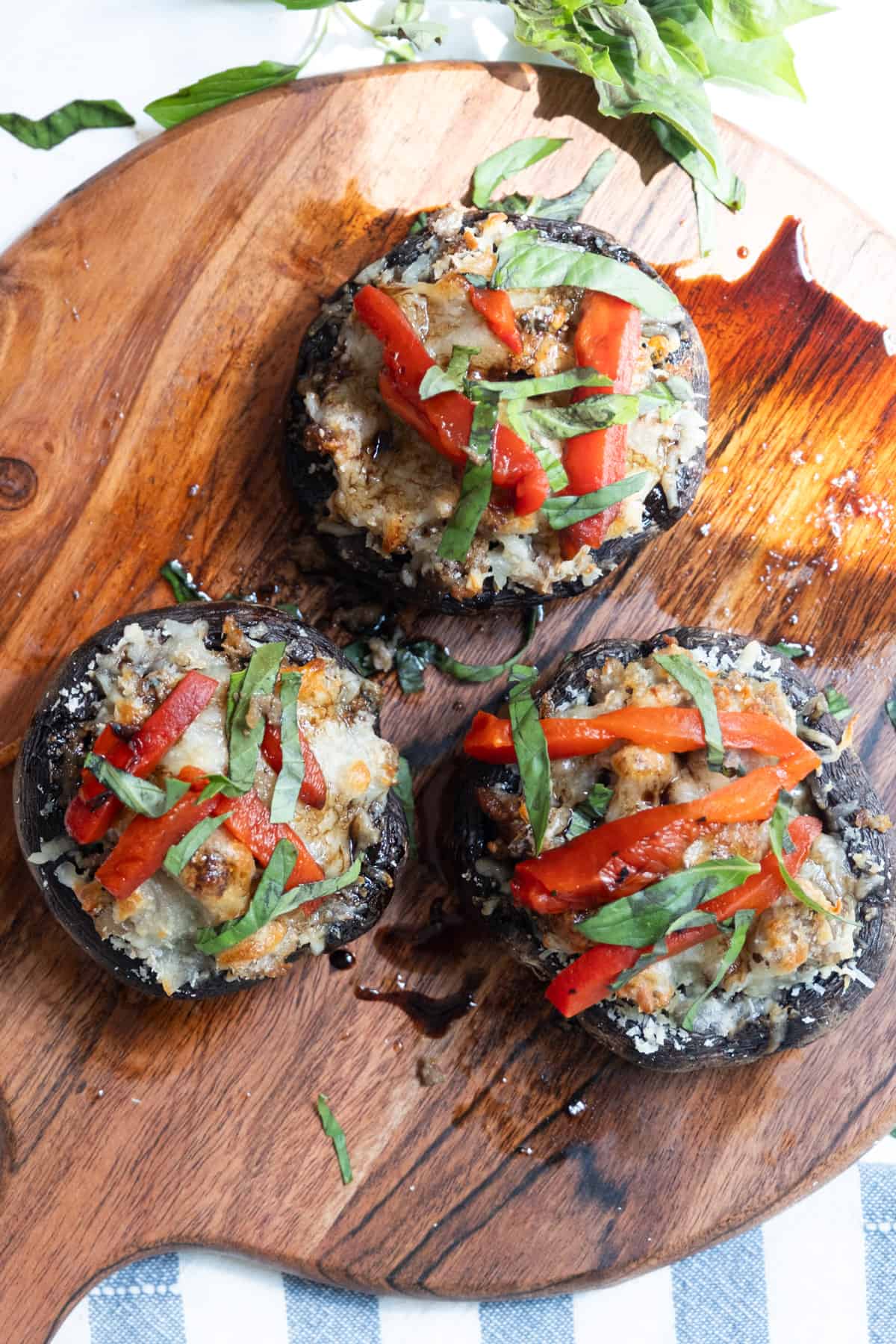 finished product: mushrooms are baked and topped with red peppers, basil, and glaze. 