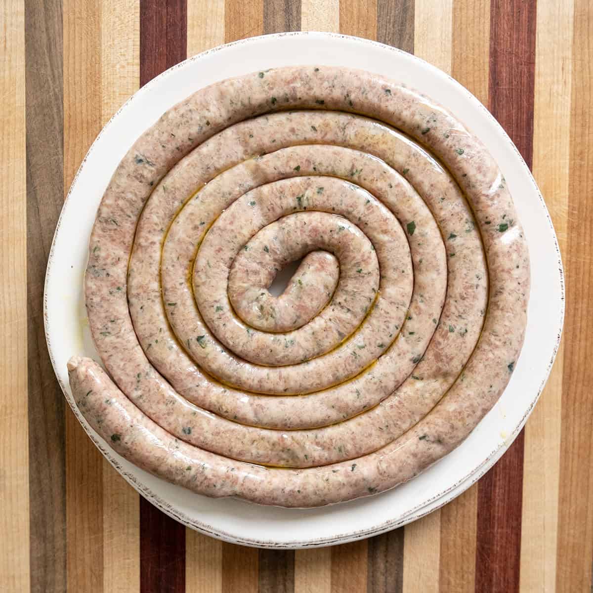 Italian sausage ring uncooked on a plate.