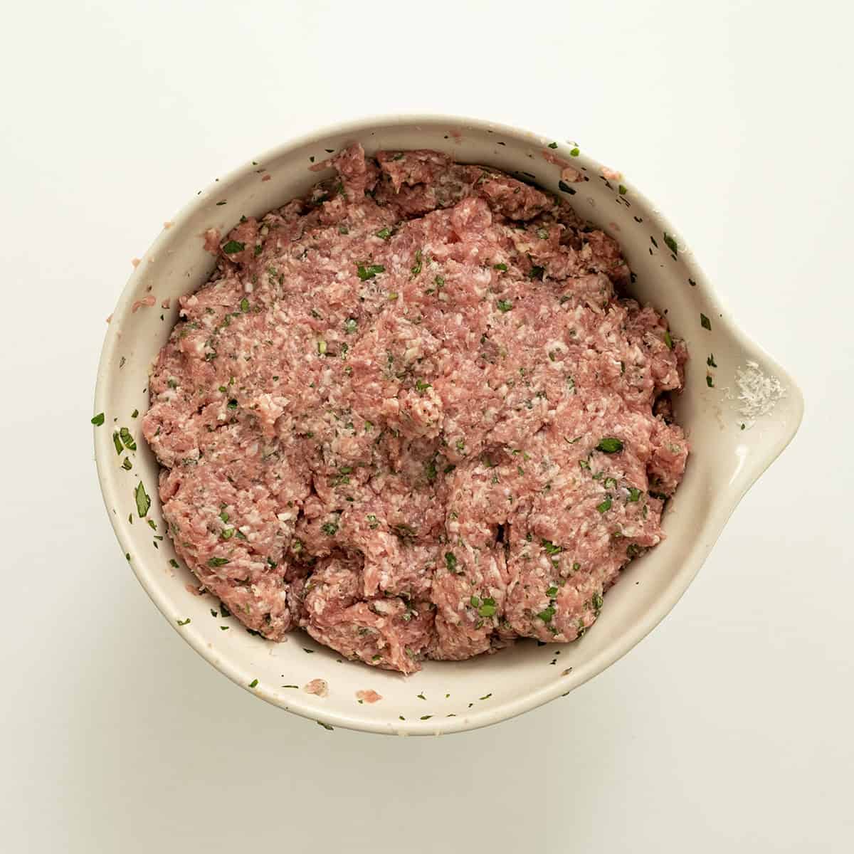 Ground pork combined with seasoning in a bowl.