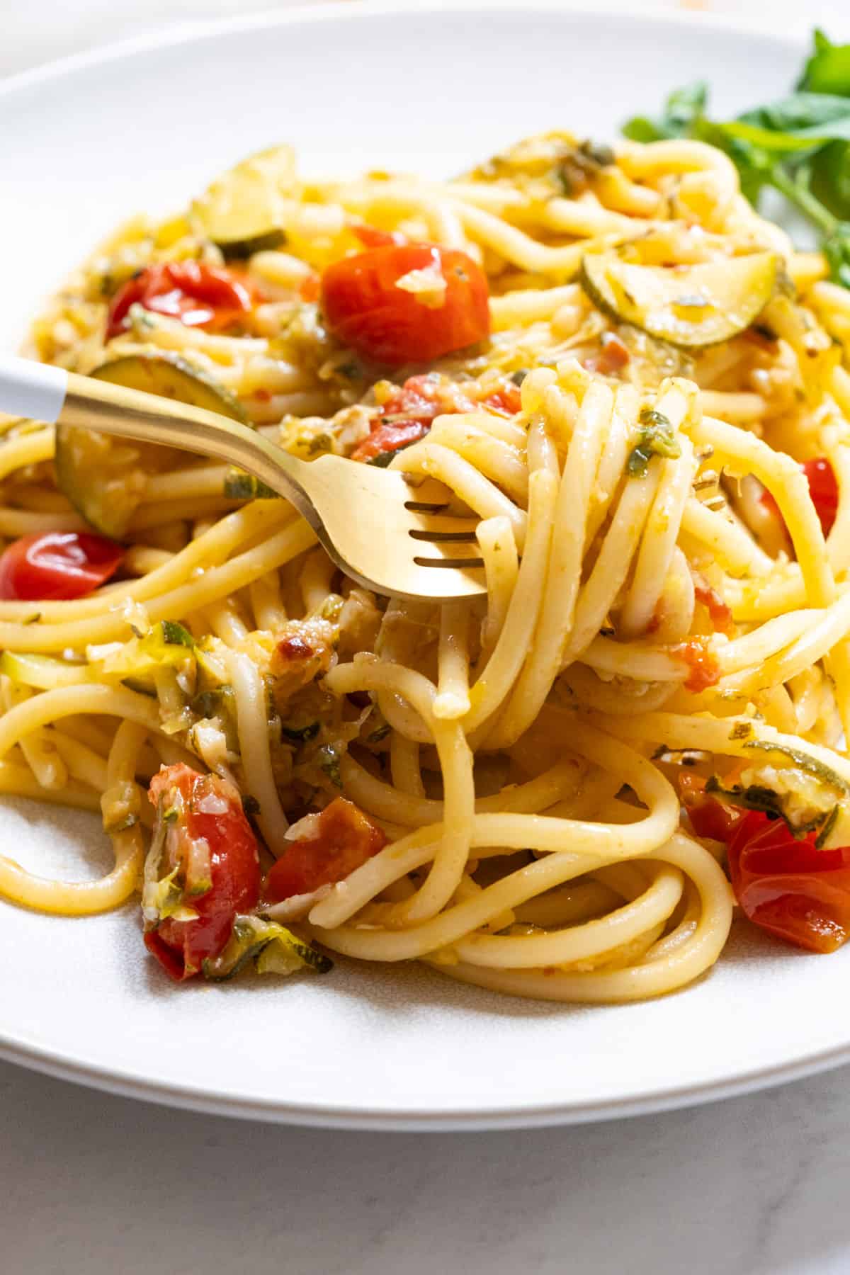 pasta with zucchini and cherry tomatoes being picked up by a fork. 