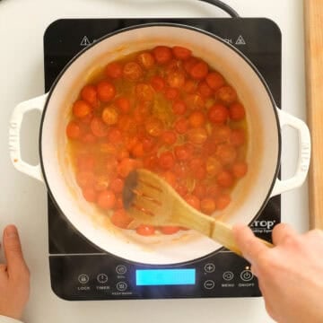 Breaking down cherry tomatoes in a dutch oven.