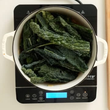 Adding kale to dutch oven.