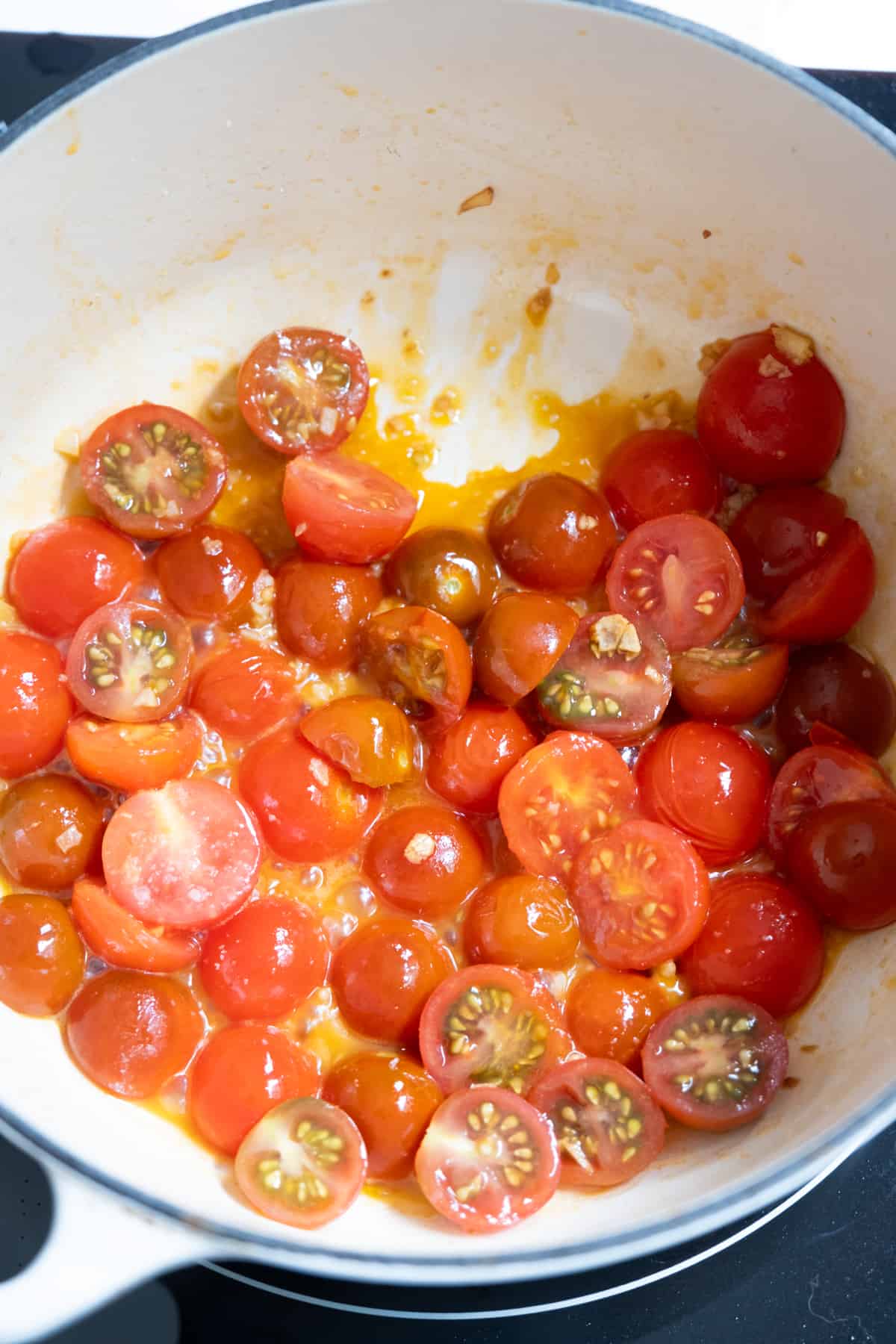 Simmering cherry tomatoes with oil and garlic