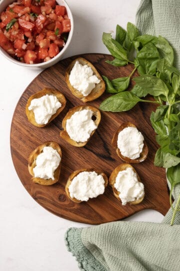 Toast on a cutting board topped with ricotta.